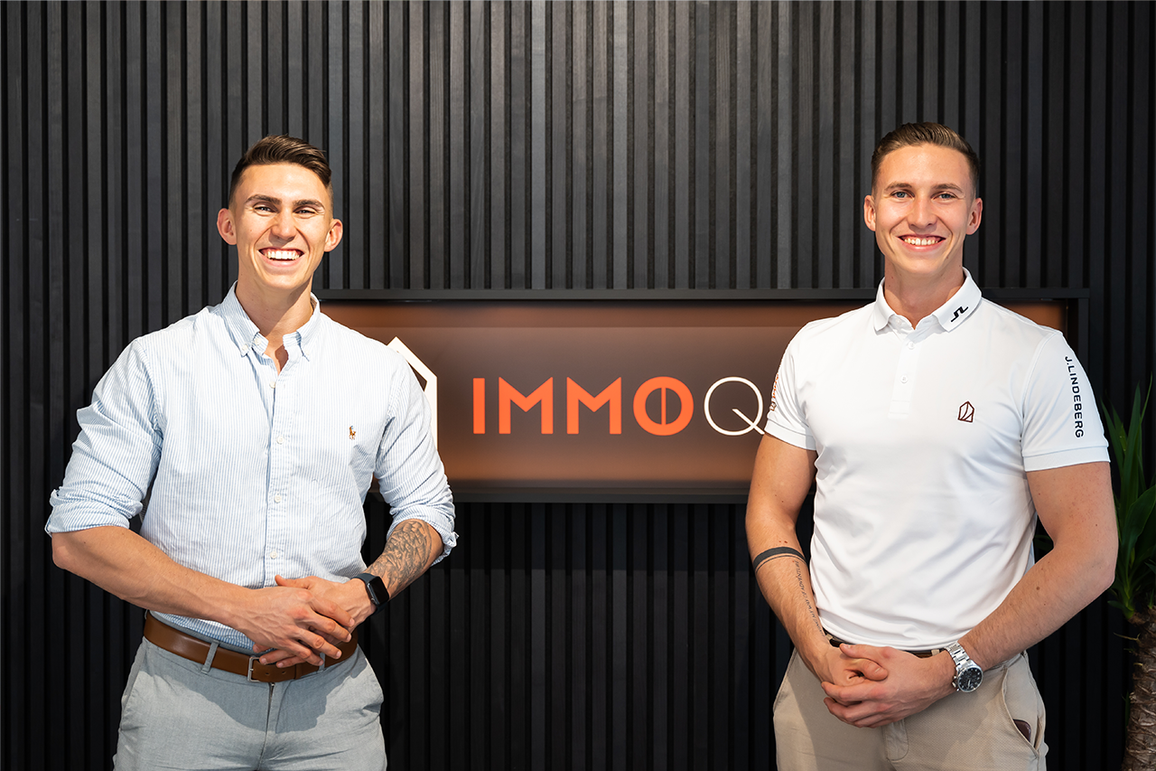 Jürgen Nussbaumer und Matthias Nussbaumer posieren vor dem IMMOQUELLE-Logo